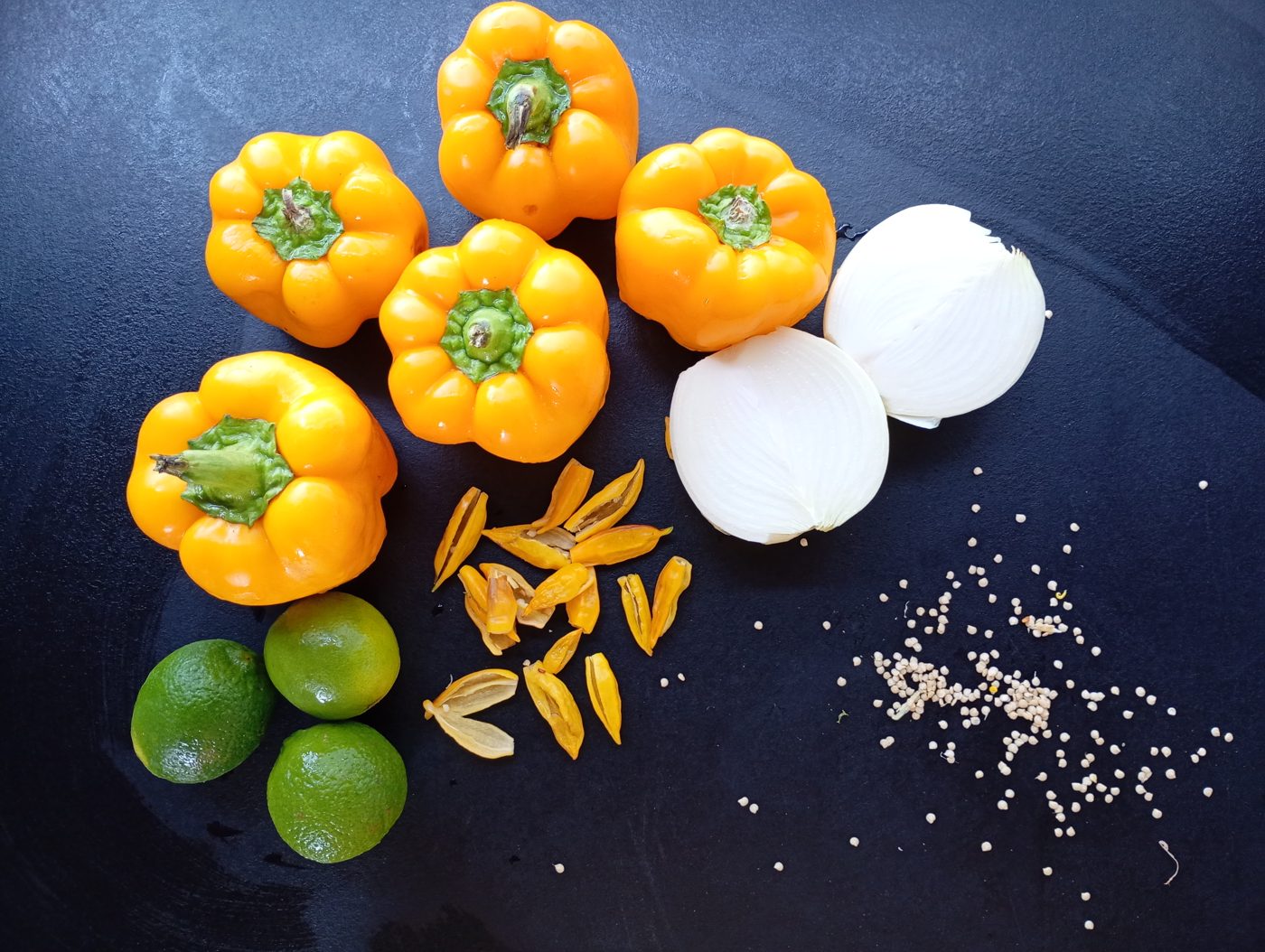 Chiles amarillos, cebolla, lima y sésamo tostado preparados sobre una tabla antes de cocinar la salsa ají limo